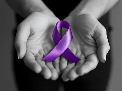 Hands holding a purple awareness ribbon symbolizing support and advocacy