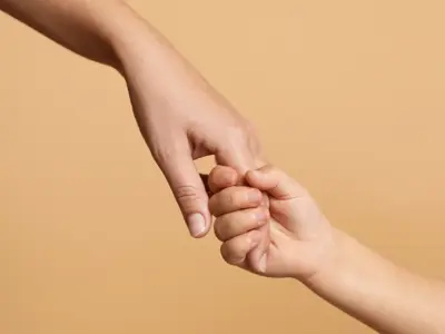 Adult hand holding a child’s hand for guidance and support