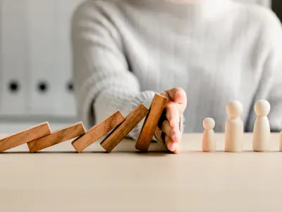 Falling dominoes stopped by a hand, symbolizing prevention or protection
