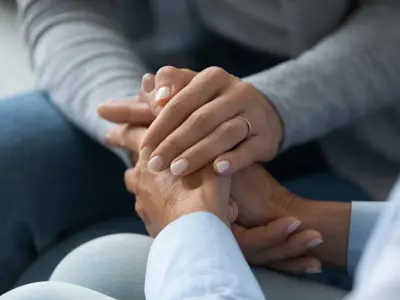 Person offering comfort and support by holding another person’s hands