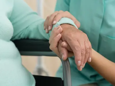 Caregiver holding an older adult’s hand for support and assistance